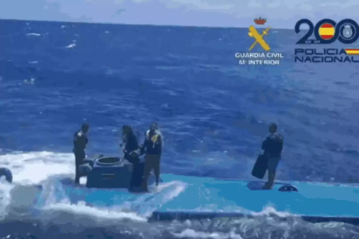 Un grupo de personas en un submarino en el mar con logotipos de la Guardia Civil y Policía Nacional en la esquina superior derecha.