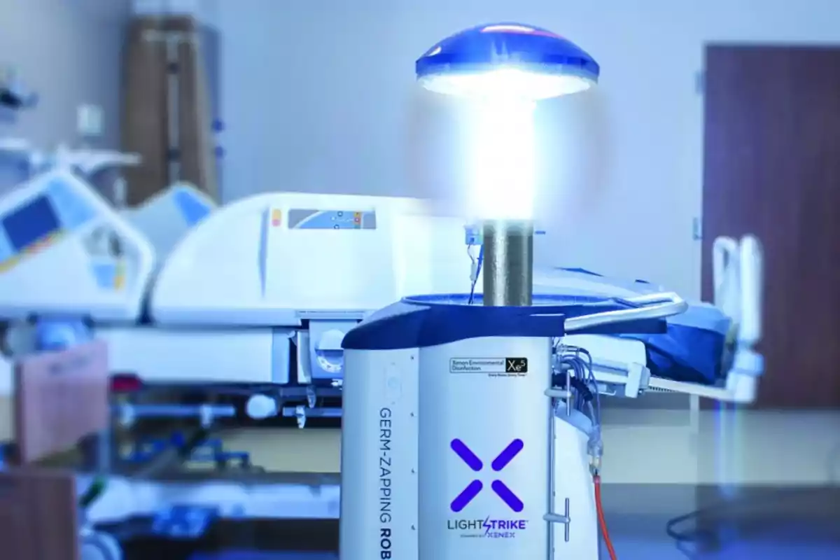 Un robot de desinfección con luz ultravioleta está operando en una habitación de hospital, con una cama médica y equipo en el fondo.