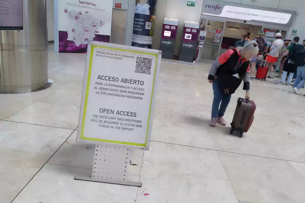 Una mujer con una maleta camina cerca de un cartel que indica Una mujer con una maleta camina cerca de un cartel que indica