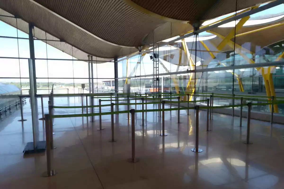 Área de espera vacía en un aeropuerto con cintas de separación y techo ondulado. Área de espera vacía en un aeropuerto con cintas de separación y techo ondulado.