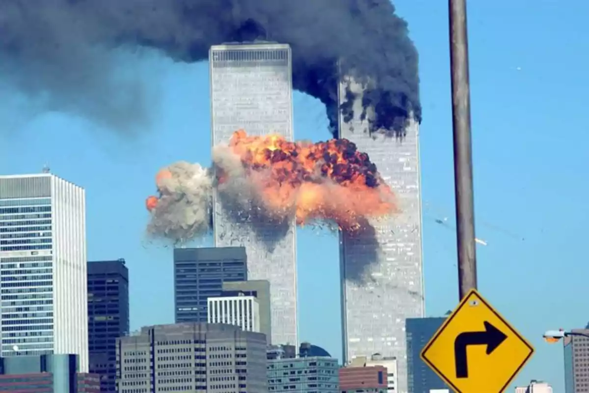 Imagen de las Torres Gemelas durante los ataques del 11 de septiembre de 2001, con una explosión visible en una de las torres y humo negro saliendo de ambas.