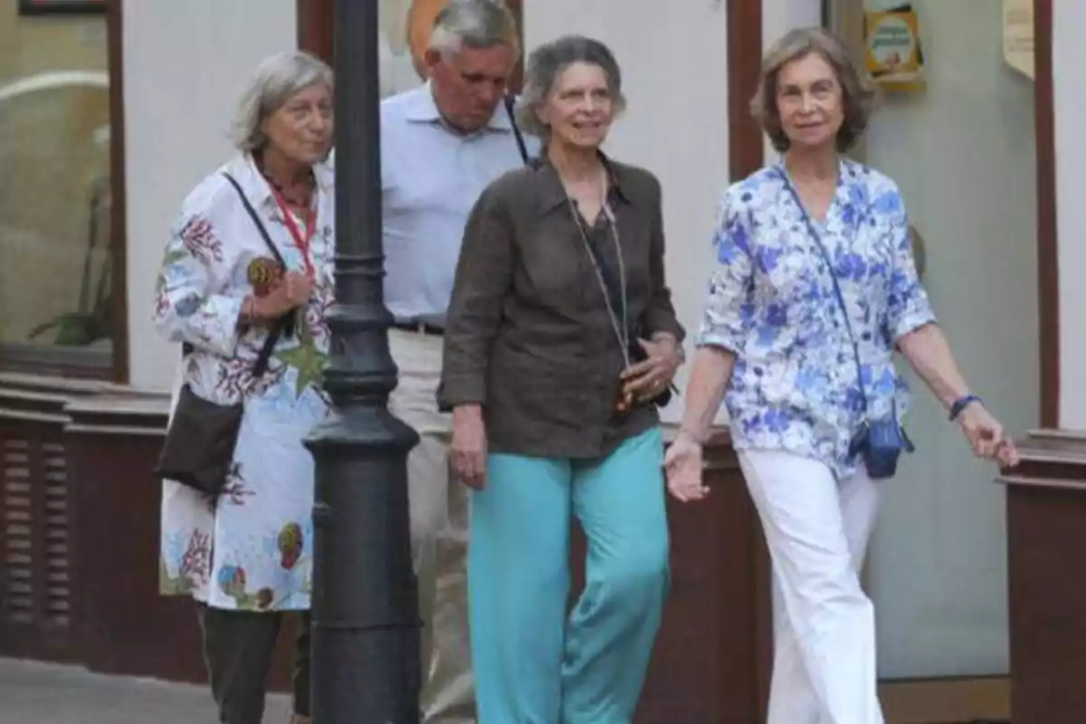 Un grupo de personas mayores caminando por la calle junto a un poste de luz.