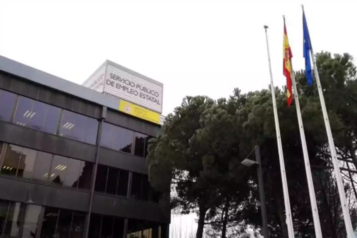 Edificio del Servicio Público de Empleo Estatal con banderas de España y la Unión Europea ondeando en el exterior.