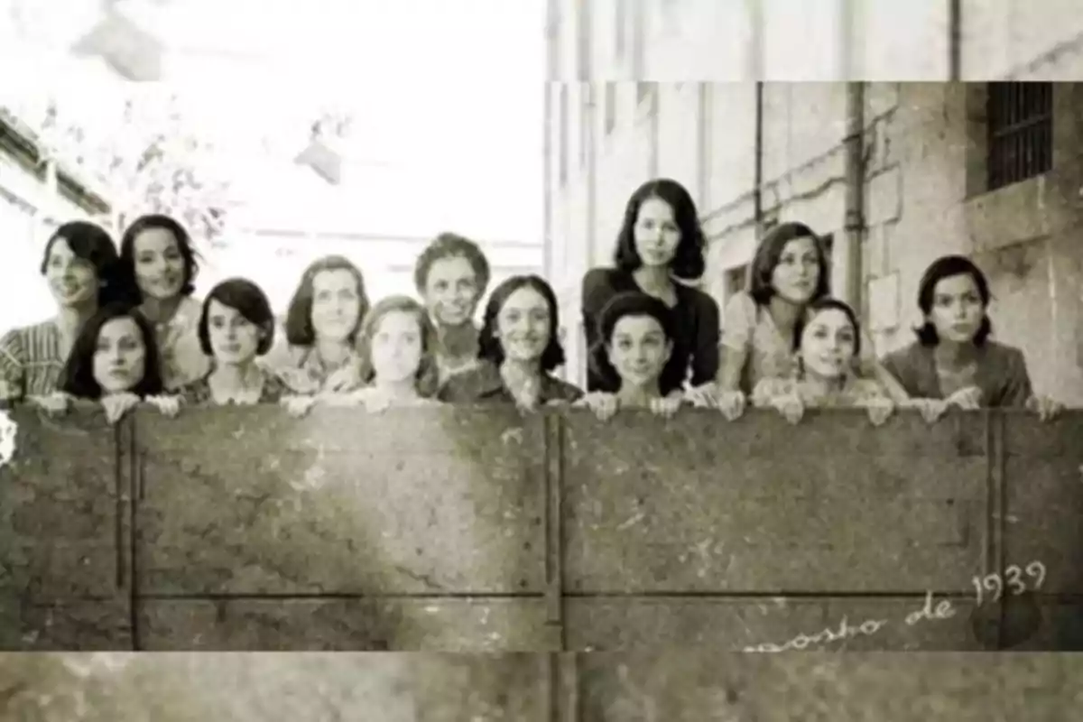 Un grupo de mujeres posando detrás de una cerca en una fotografía en blanco y negro tomada en agosto de 1939.