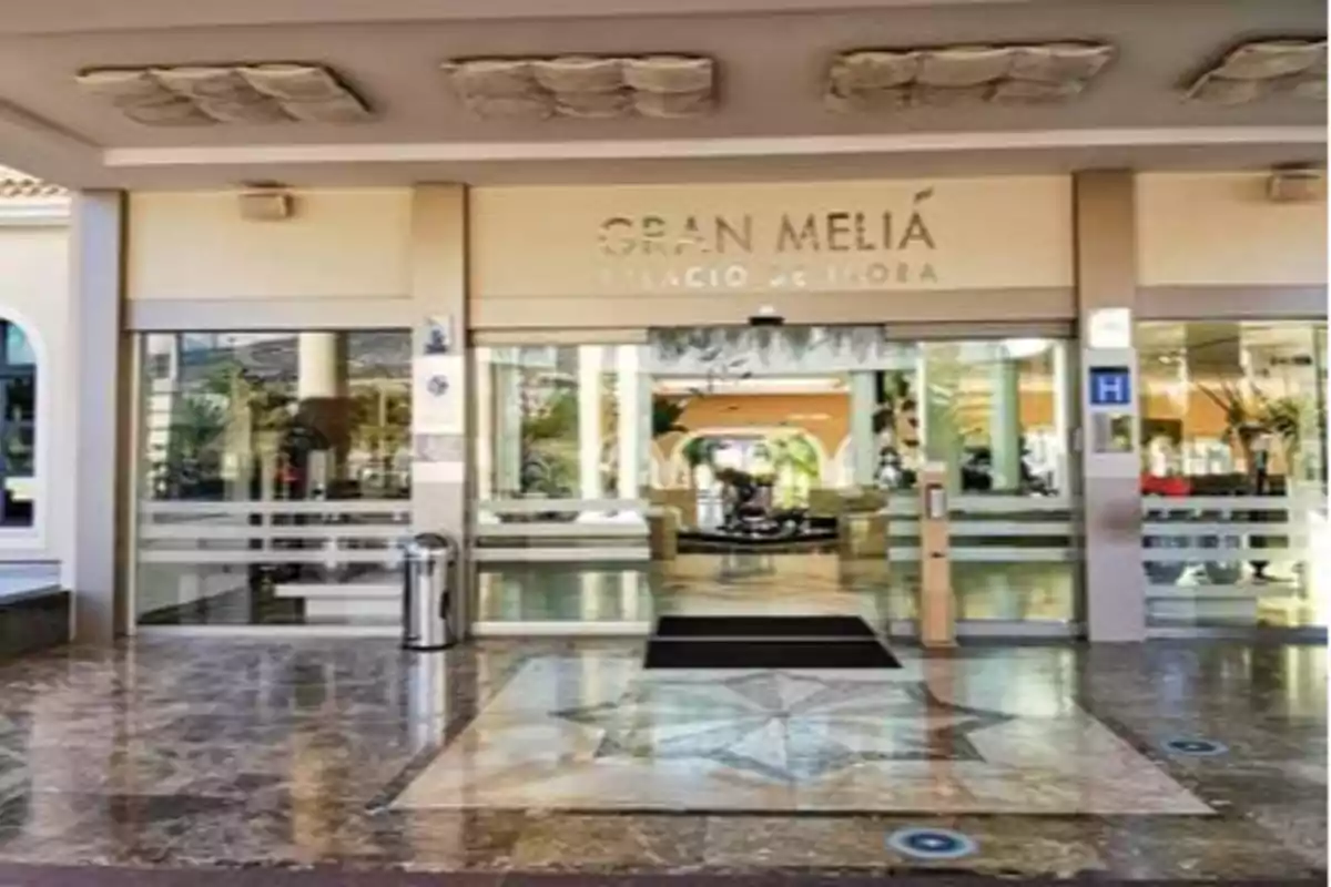 Entrada principal del hotel Gran Meliá Palacio de Isora con puertas de vidrio y piso de mármol.