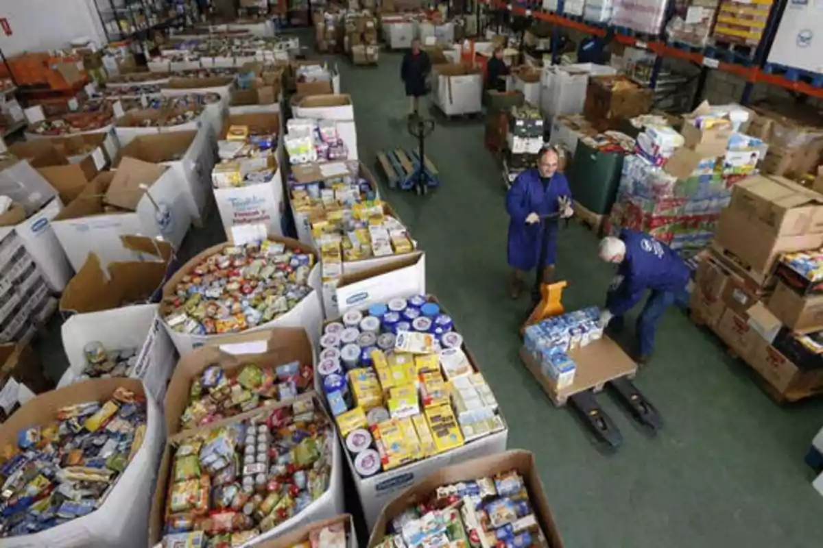 Personas trabajando en un almacén lleno de cajas y productos alimenticios.