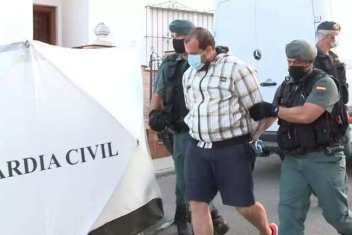 Un hombre esposado y escoltado por dos agentes de la Guardia Civil.