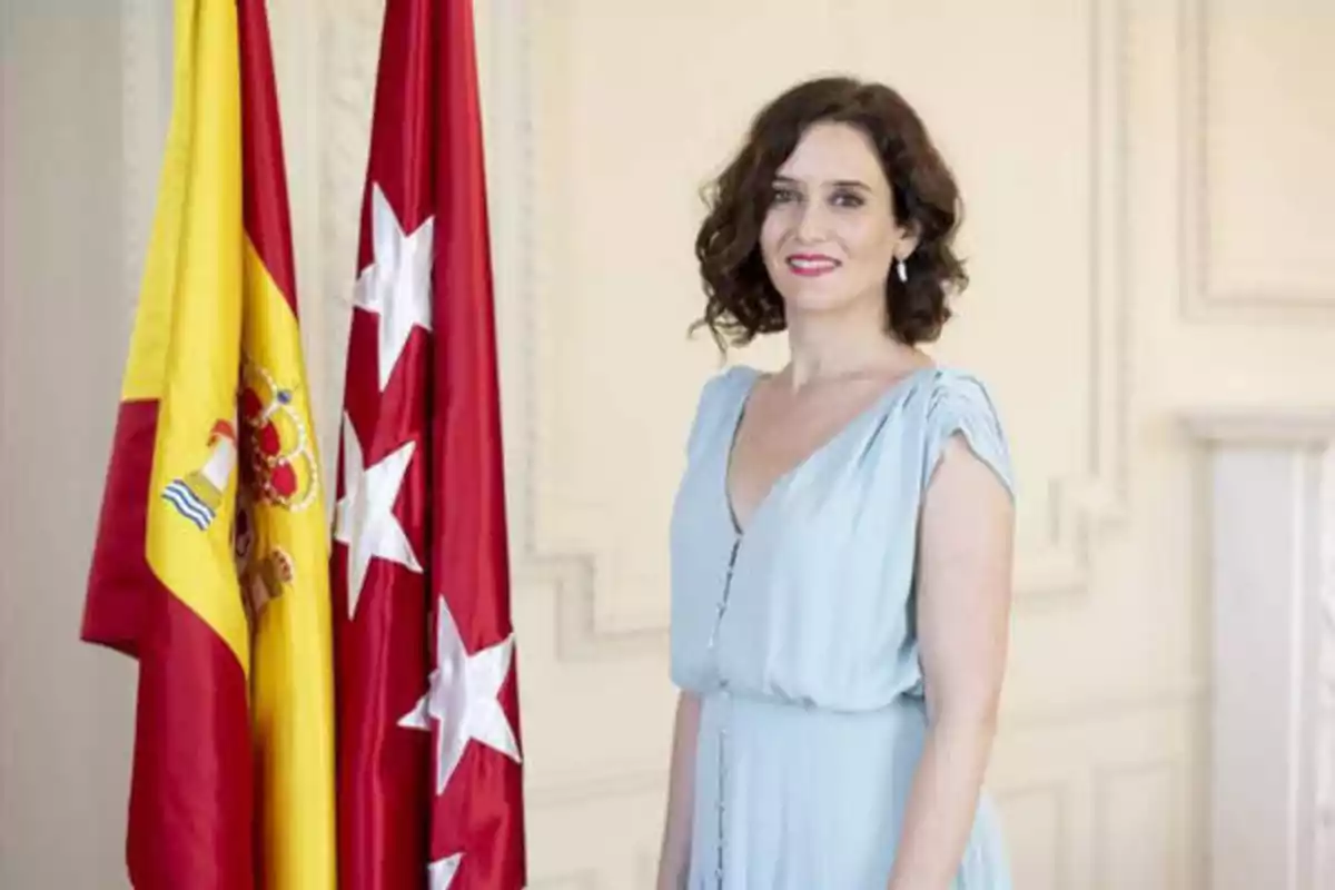 Mujer de pie junto a las banderas de España y de la Comunidad de Madrid.