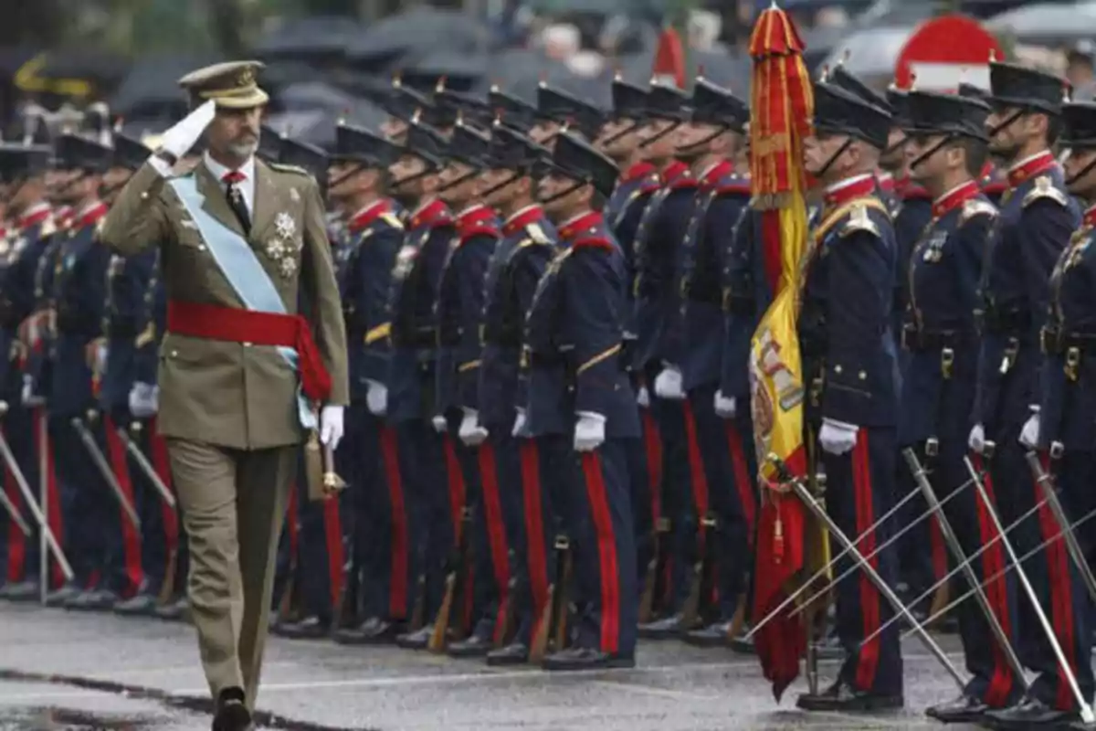 Un oficial militar saluda mientras pasa frente a una fila de soldados uniformados durante una ceremonia.