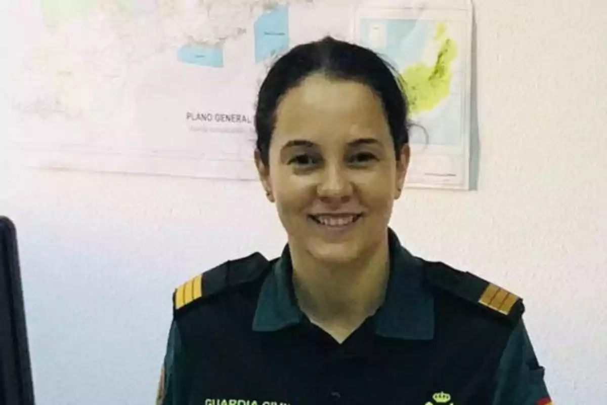 Una mujer con uniforme de la Guardia Civil sonríe frente a un mapa en la pared.