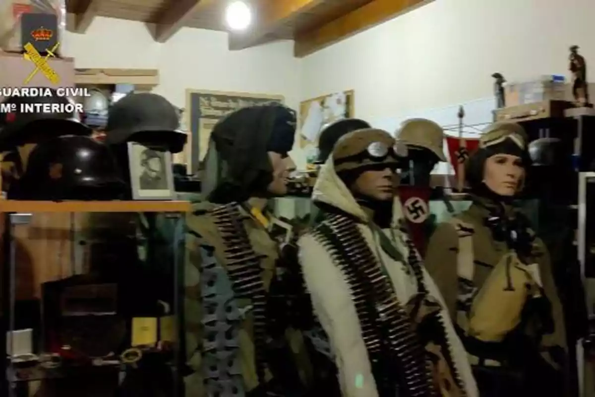 Maniquíes vestidos con uniformes militares y equipo de la Segunda Guerra Mundial en una habitación con cascos y otros objetos históricos.