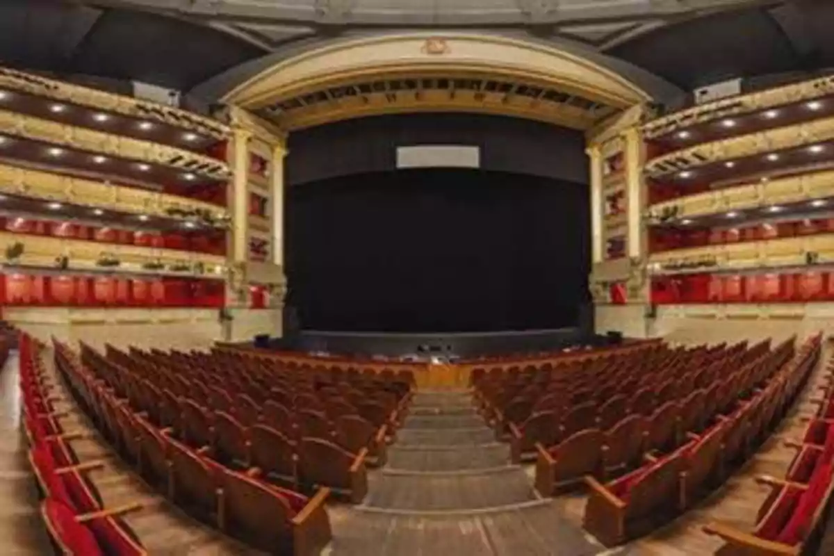 Interior de un teatro con asientos rojos y un escenario grande