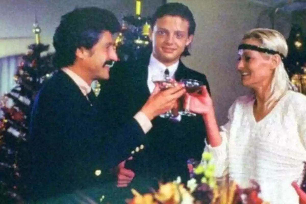 Tres personas brindando con copas de vino en una fiesta navideña con un árbol de Navidad decorado al fondo.