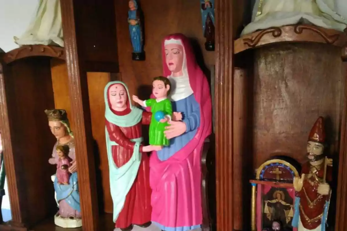 Estatuas religiosas de diferentes santos y figuras en un altar de madera.