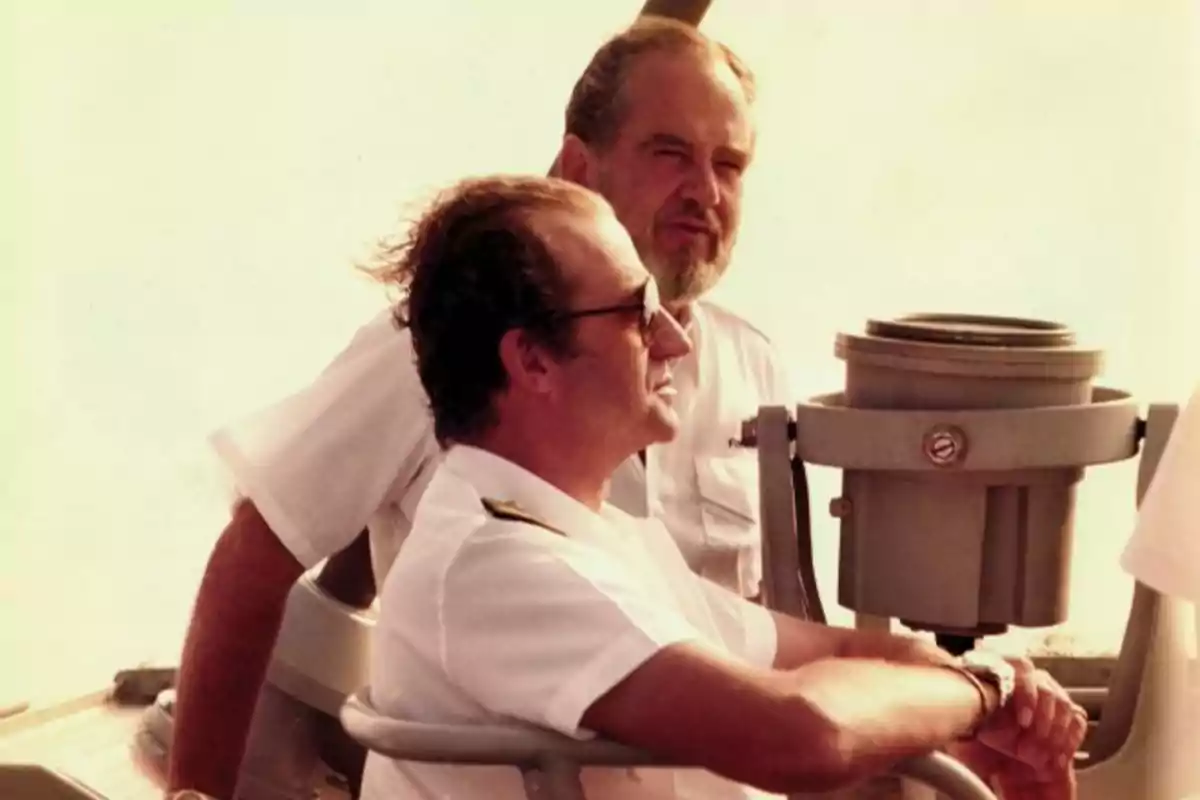 Dos hombres con uniformes blancos observan el horizonte desde un barco.