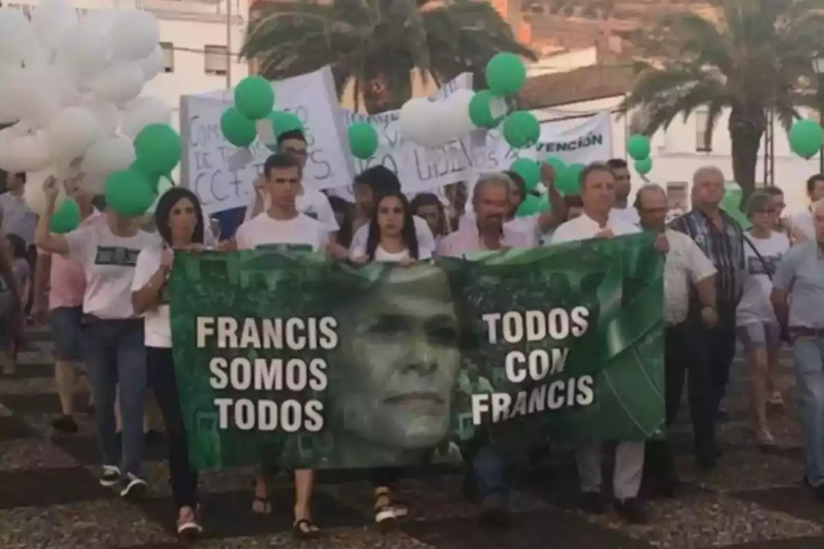 Un grupo de personas participa en una marcha sosteniendo un cartel verde con un rostro y las frases Un grupo de personas participa en una marcha sosteniendo un cartel verde con un rostro y las frases