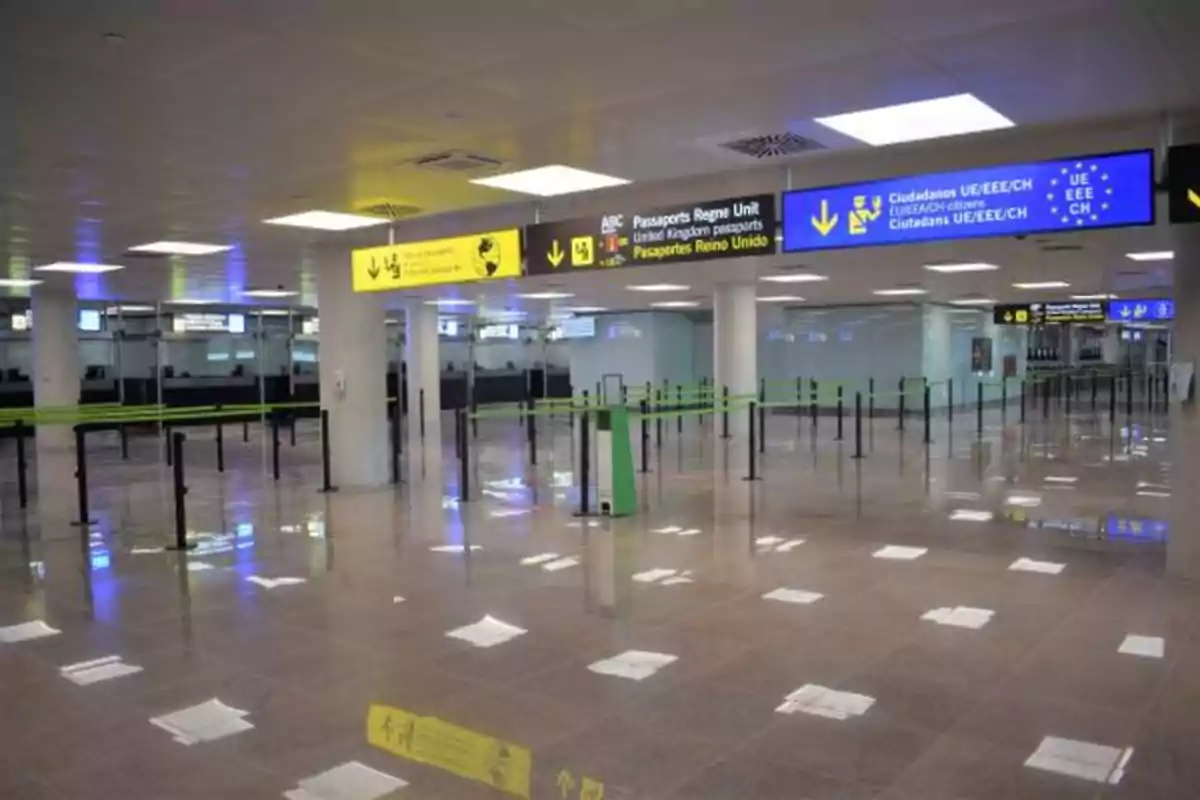 Área de control de pasaportes en un aeropuerto con señalización para diferentes nacionalidades y filas de espera vacías.