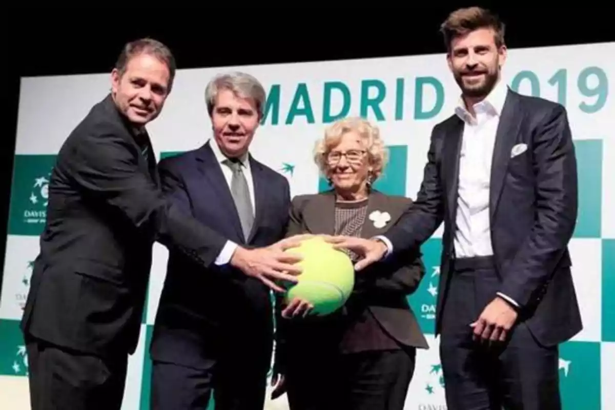 Cuatro personas posan juntas sosteniendo una pelota de tenis gigante frente a un cartel que dice "Madrid 2019".