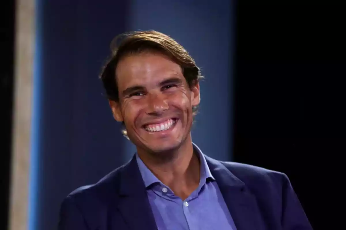 Hombre sonriendo con traje azul y camisa azul claro.