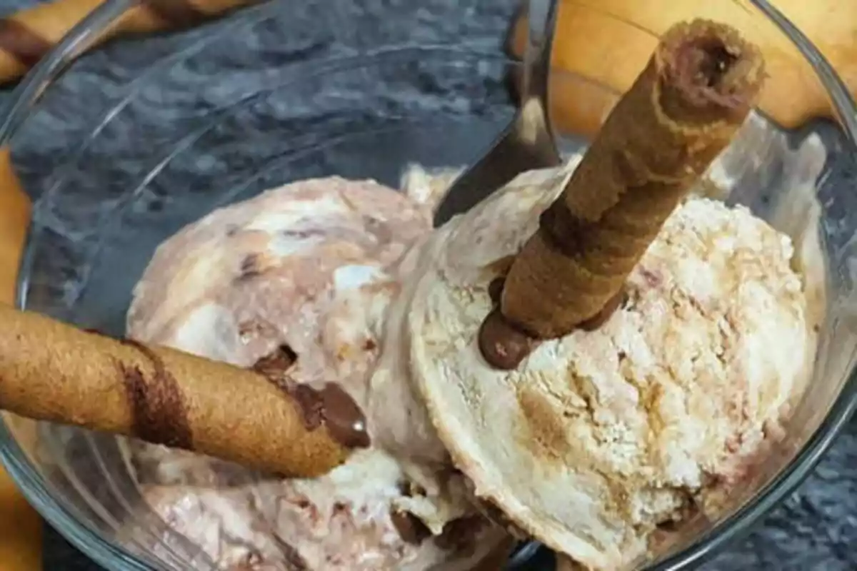 Helado de vainilla y chocolate con barquillos de chocolate en un tazón de vidrio.