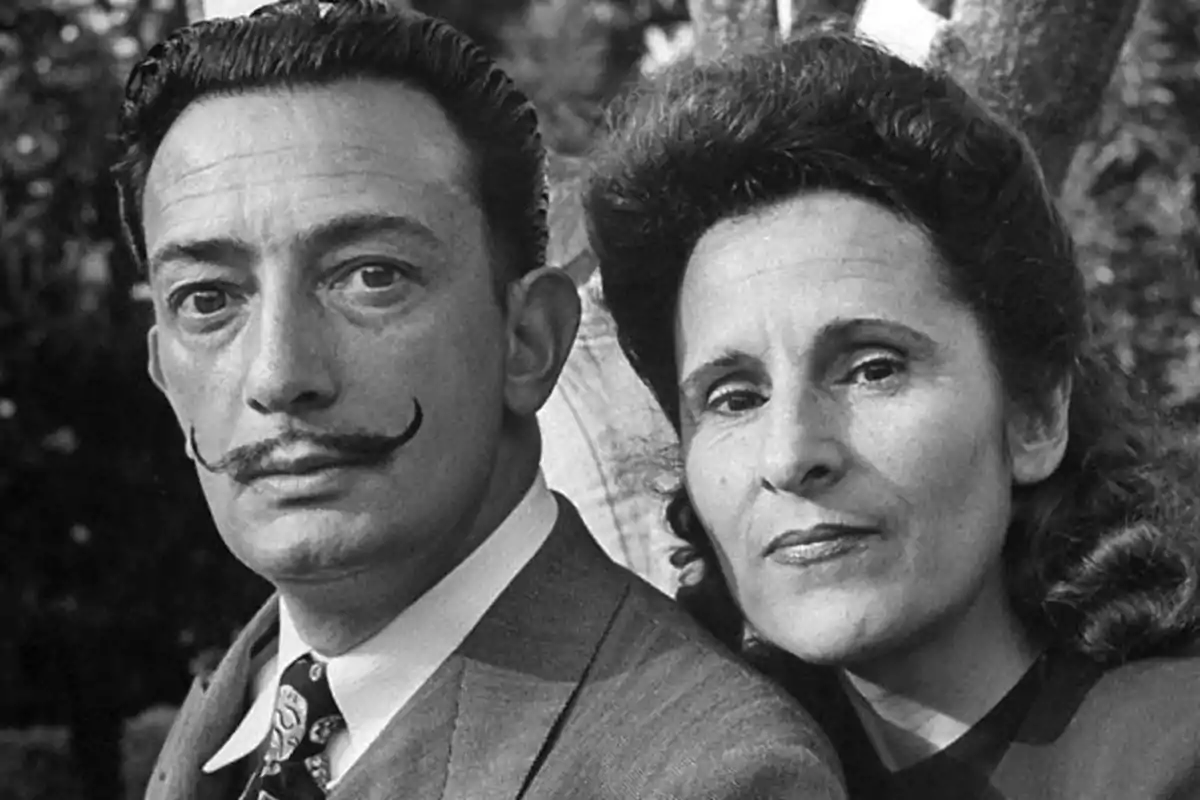 Un hombre con bigote y una mujer posan juntos en una fotografía en blanco y negro. Un hombre con bigote y una mujer posan juntos en una fotografía en blanco y negro.