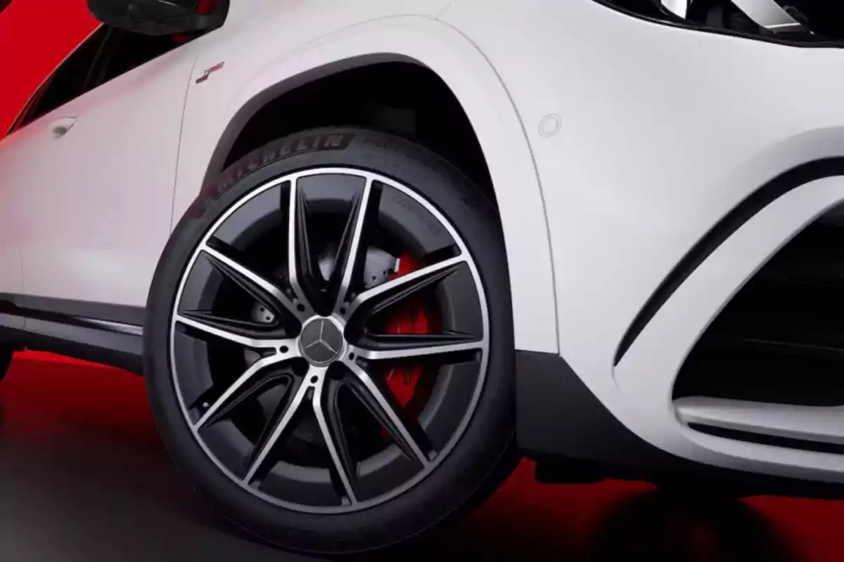 Primer plano de la llanta de un automóvil blanco con un diseño deportivo y fondo rojo. Primer plano de la llanta de un automóvil blanco con un diseño deportivo y fondo rojo.