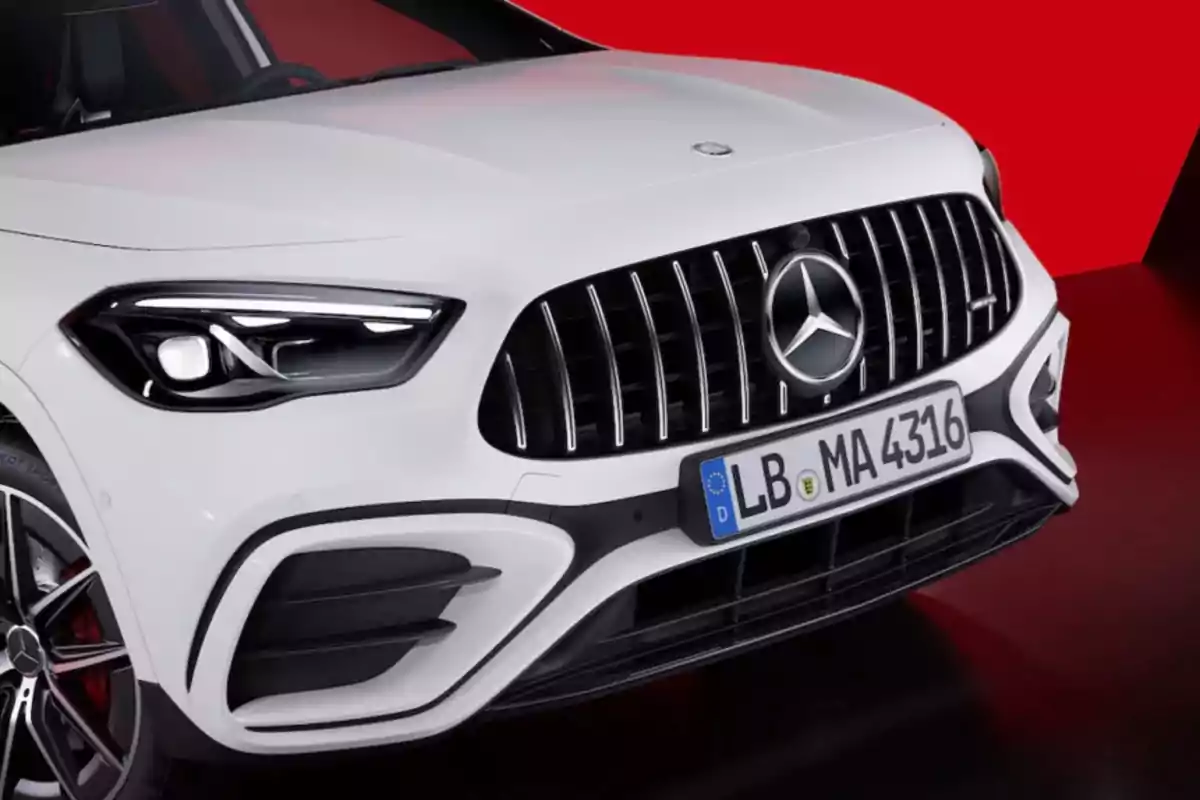 Frontal de un automóvil blanco con parrilla distintiva y placa de matrícula sobre un fondo rojo. Frontal de un automóvil blanco con parrilla distintiva y placa de matrícula sobre un fondo rojo.