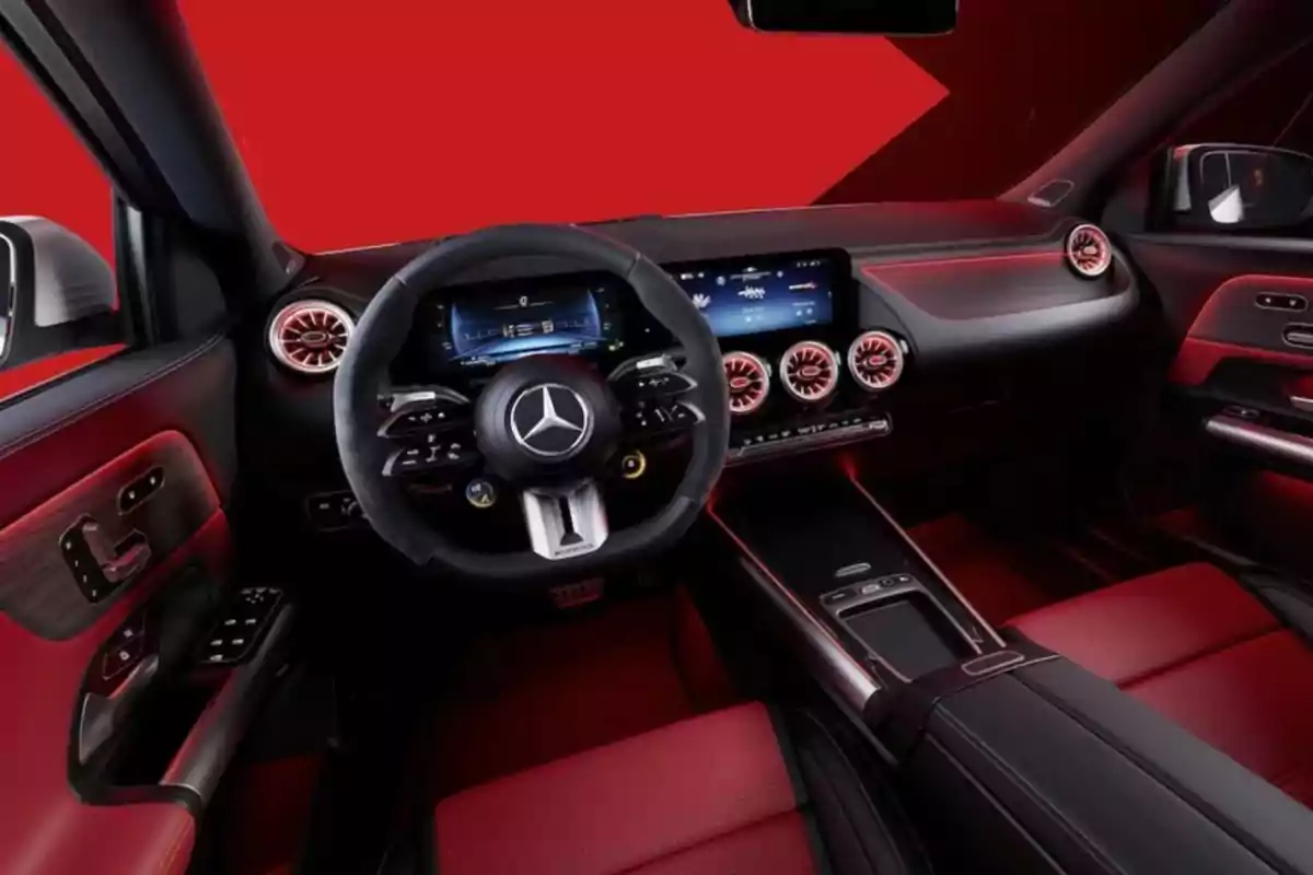Interior de un automóvil de lujo con diseño moderno y detalles en rojo y negro, volante con logotipo en el centro, pantallas digitales y salidas de aire circulares iluminadas. Interior de un automóvil de lujo con diseño moderno y detalles en rojo y negro, volante con logotipo en el centro, pantallas digitales y salidas de aire circulares iluminadas.