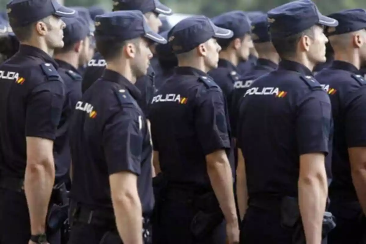 Un grupo de policías en formación, vestidos con uniformes oscuros y gorras.