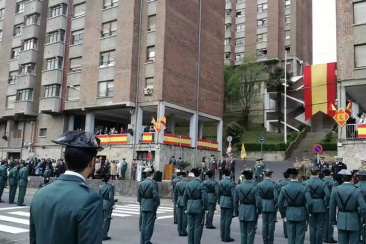 Desfile de la Guardia Civil frente a un edificio con banderas de España.