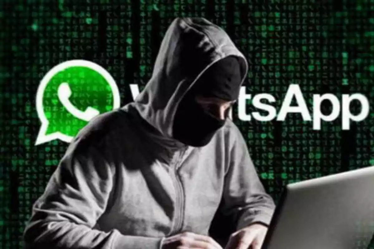 Persona con capucha y máscara usando una computadora portátil con el logo de WhatsApp en el fondo.