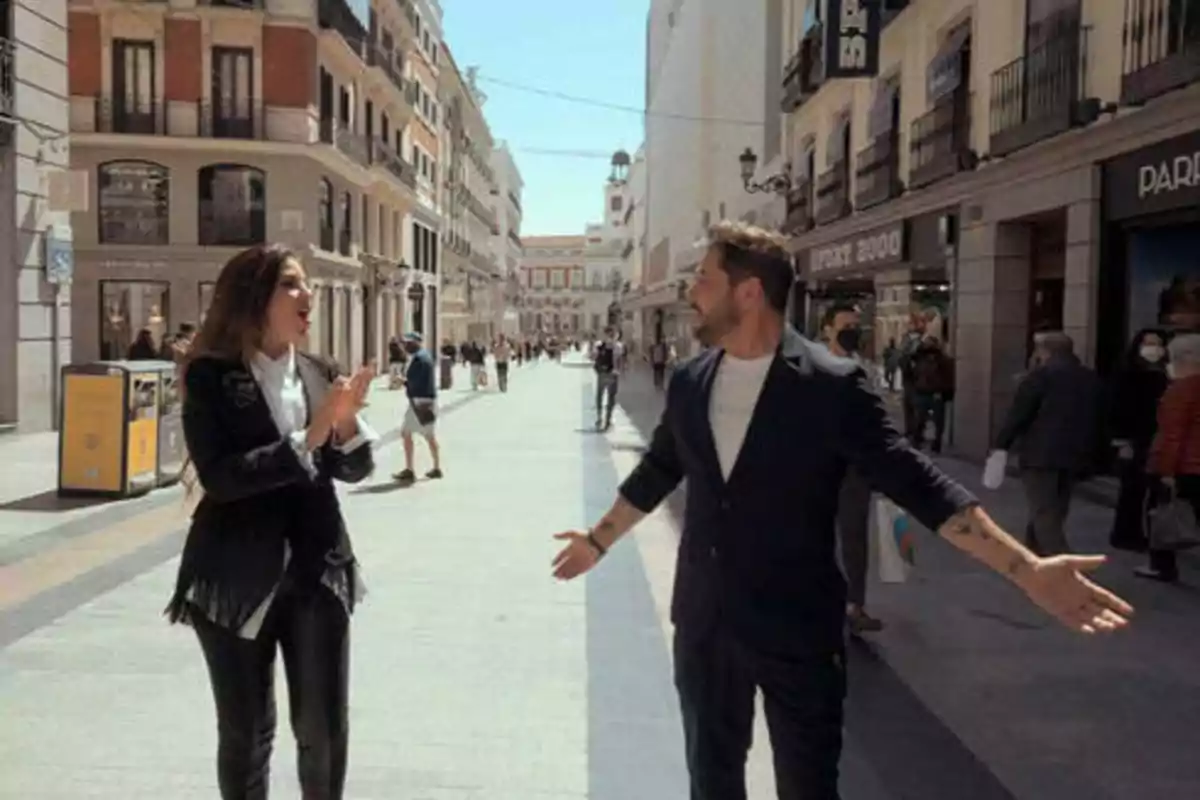Dos personas conversando animadamente en una calle concurrida de una ciudad.