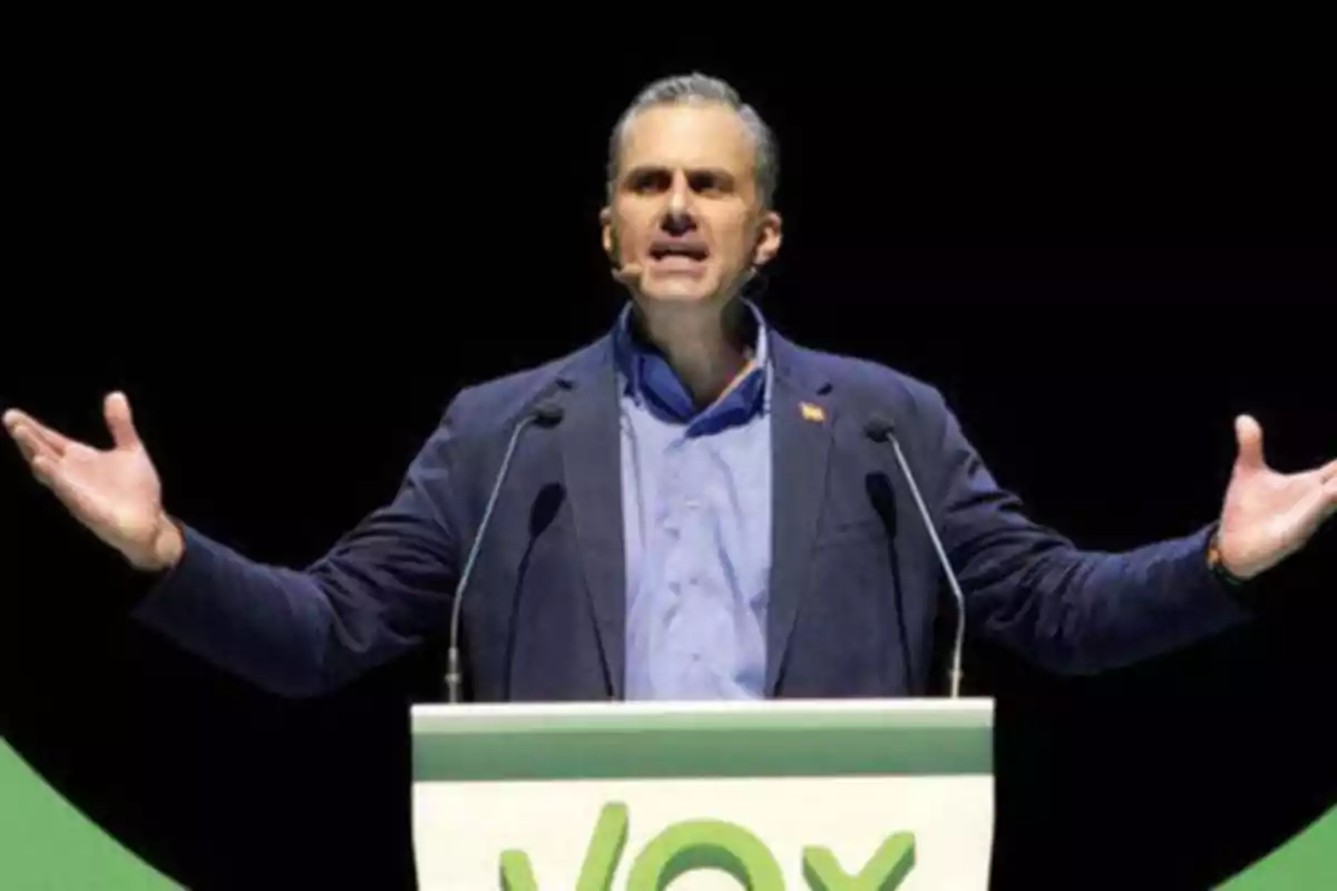 Hombre hablando en un podio con el logo de VOX.