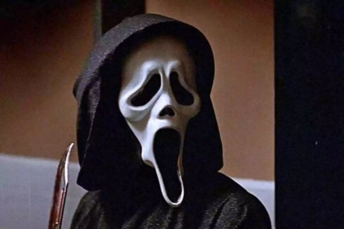 Persona con máscara de fantasma y capucha negra sosteniendo un cuchillo.