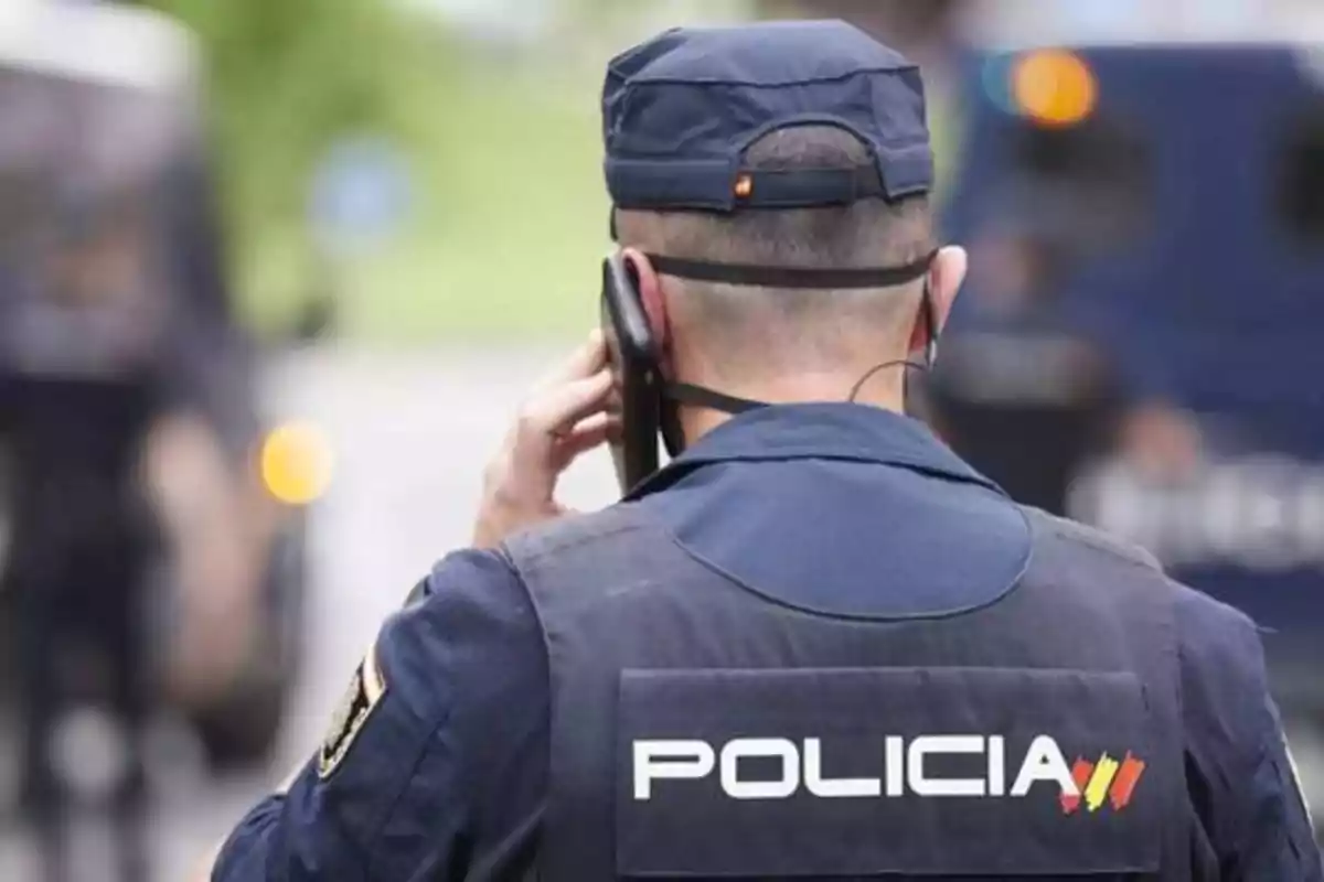Un policía de espaldas hablando por teléfono.