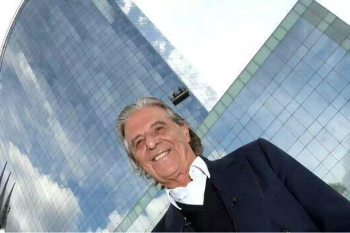 Hombre sonriendo frente a un edificio de cristal.
