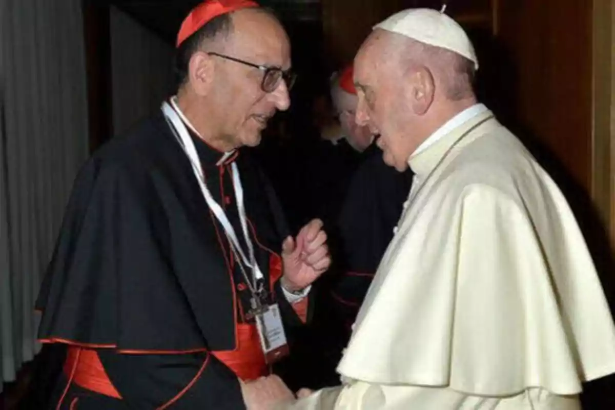 Dos clérigos católicos conversando y estrechándose la mano.