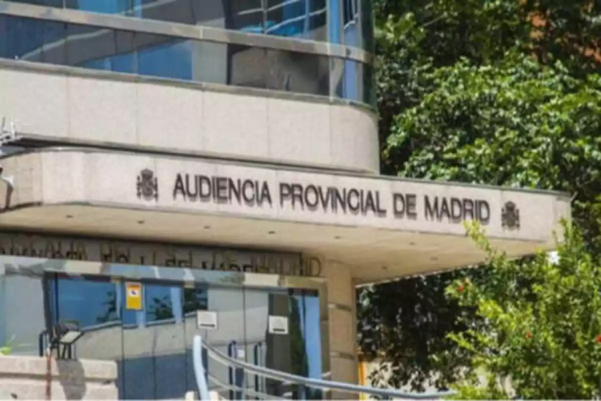 Fachada de la Audiencia Provincial de Madrid con árboles y vegetación alrededor.