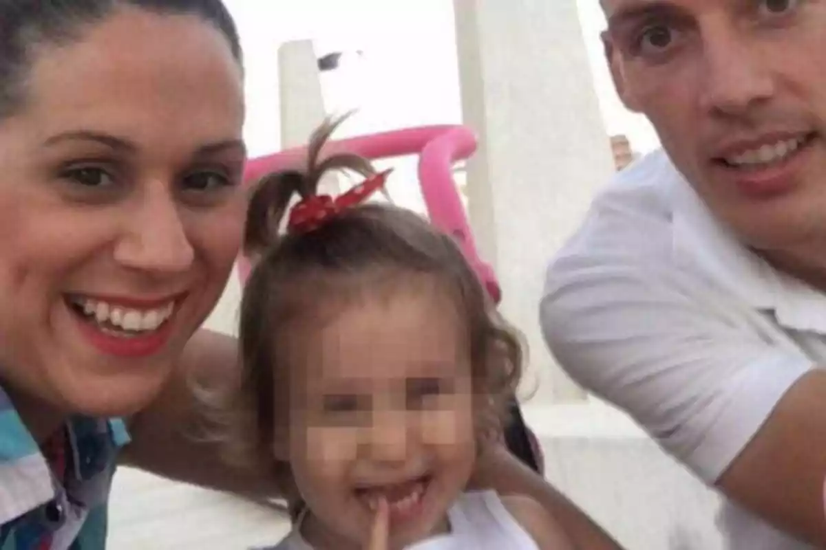 Una familia sonriente toma una selfie al aire libre, con una niña pequeña en el centro que tiene la cara pixelada.