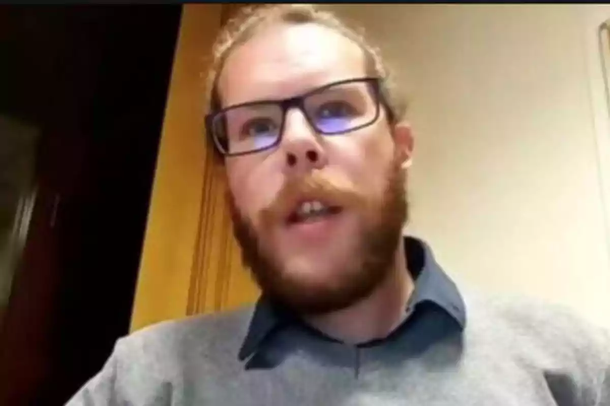 Hombre con barba y gafas hablando frente a una cámara.