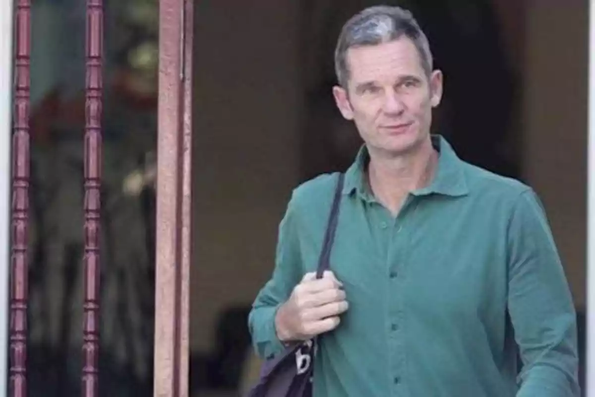 Un hombre con camisa verde y bolso negro sale de un edificio.