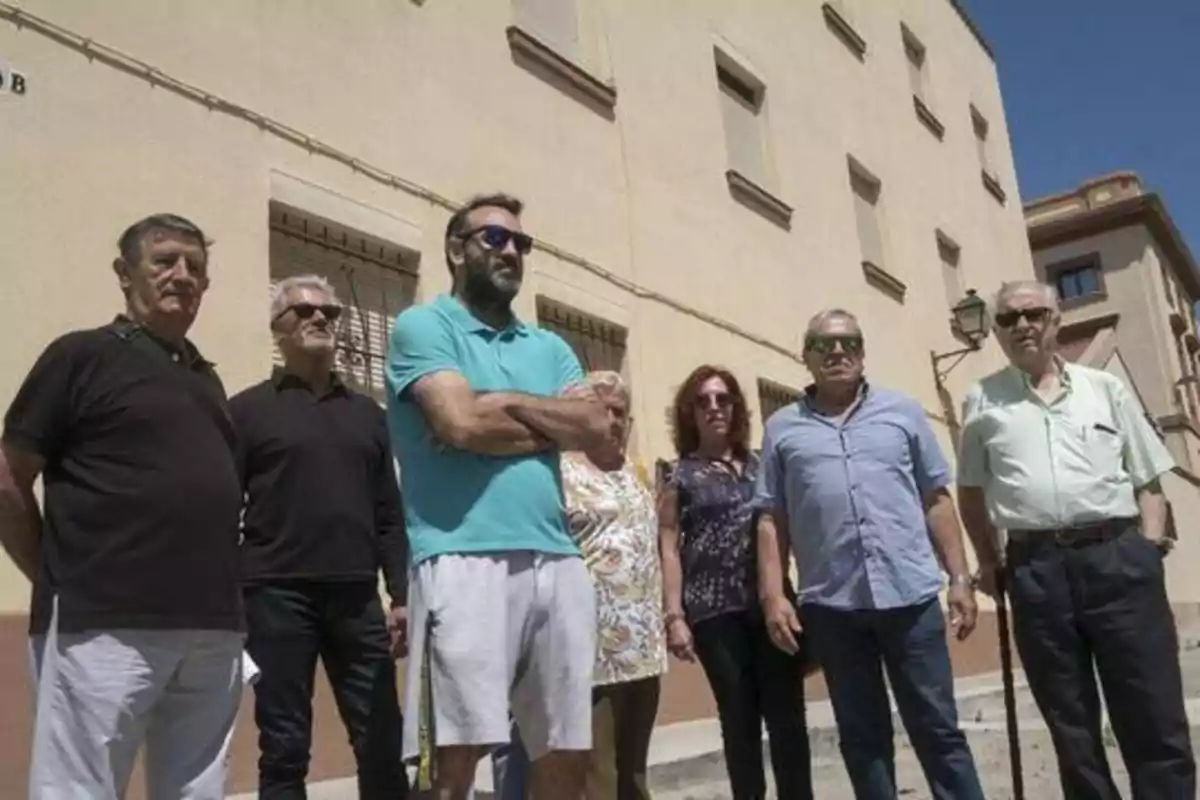 Un grupo de personas posando frente a un edificio beige en un día soleado.