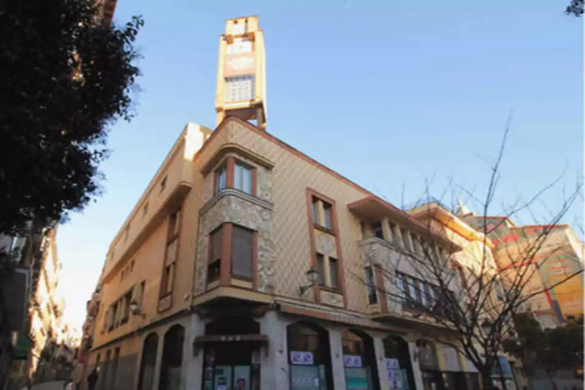 Edificio de esquina con fachada decorada y torre con reloj en una calle urbana.