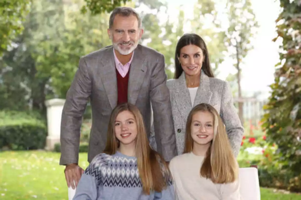 Una familia posando al aire libre con árboles y vegetación de fondo.