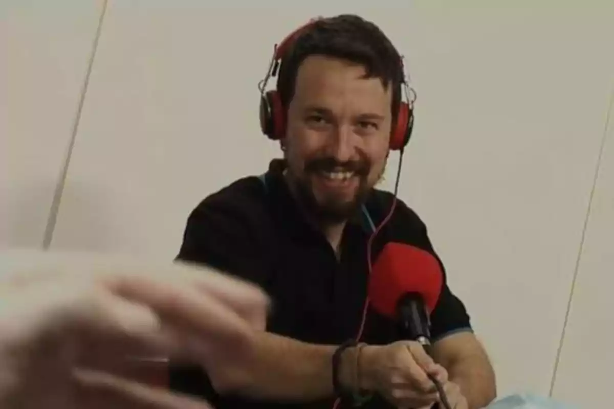 Persona con auriculares rojos y micrófono rojo sonriendo mientras habla.
