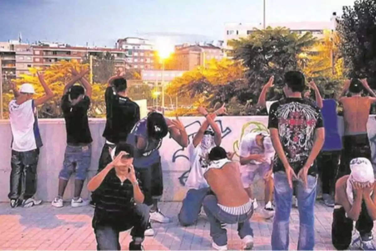 Un grupo de jóvenes posando en una zona urbana con edificios y árboles al fondo.