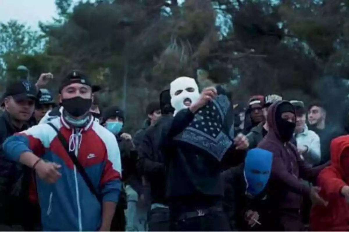 Un grupo de personas con máscaras y ropa casual se encuentran reunidas al aire libre.