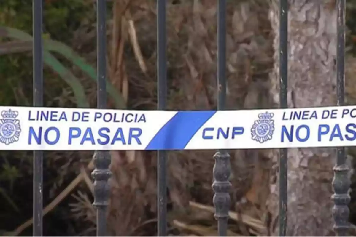 Cinta de policía con la inscripción "Línea de Policía No Pasar" atada a una reja.