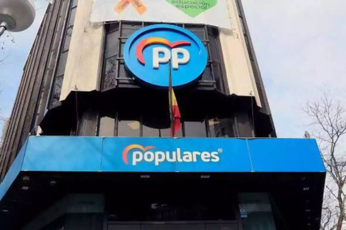 Edificio con el logotipo del Partido Popular y un cartel que dice "populares" en la fachada.