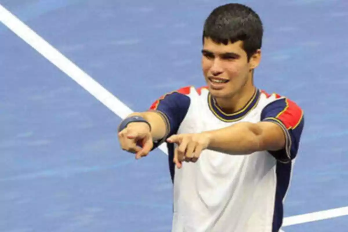 Un jugador de tenis celebrando en una cancha azul.